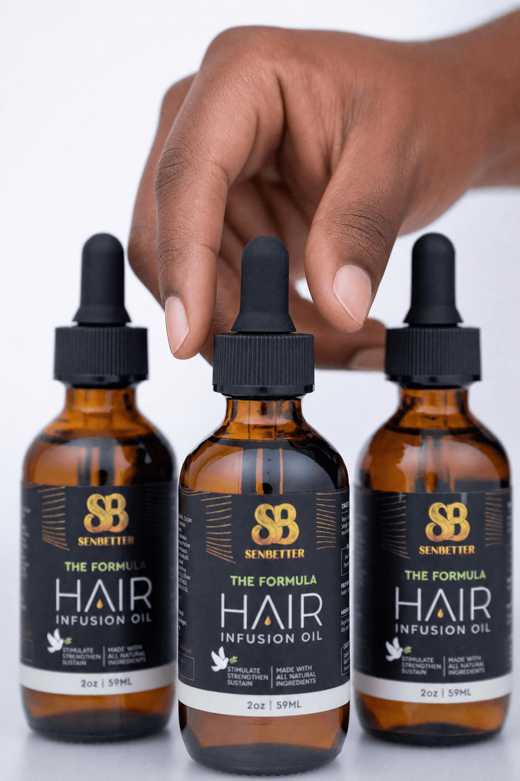 Three amber glass dropper bottles of Senbiter Hair Infusion Oil arranged in a row, with a hand reaching toward the center bottle against a clean white background.