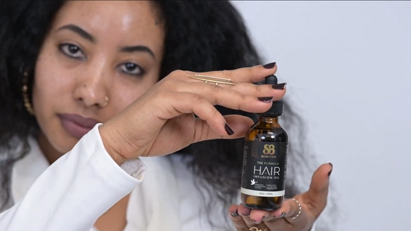 Woman applying The Formula rosemary and mint hair oil to her scalp