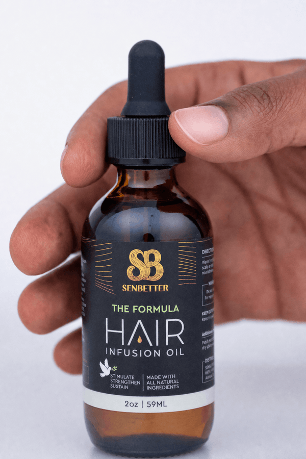 Hand holding The Formula rosemary hair oil bottle with dropper