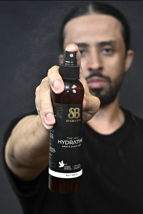 Man holding The Mist hydrating hair spray bottle