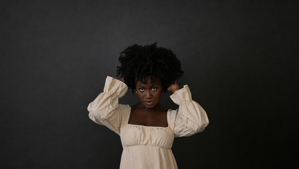 Woman with voluminous natural afro hair holding her hair up showing healthy hair growth with Senbetter